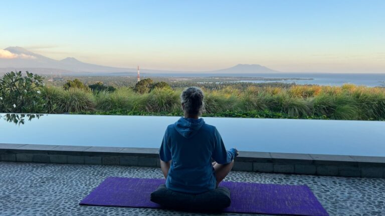 A woman seated with good posture, admiring a breathtaking tropical landscape in the background.