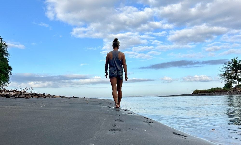 A woman enjoying a peaceful barefoot walk along the sandy beach.