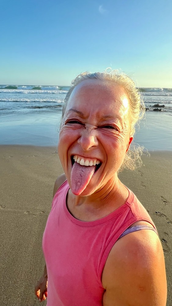 Woman on a beach playfully sticking out her tongue.
