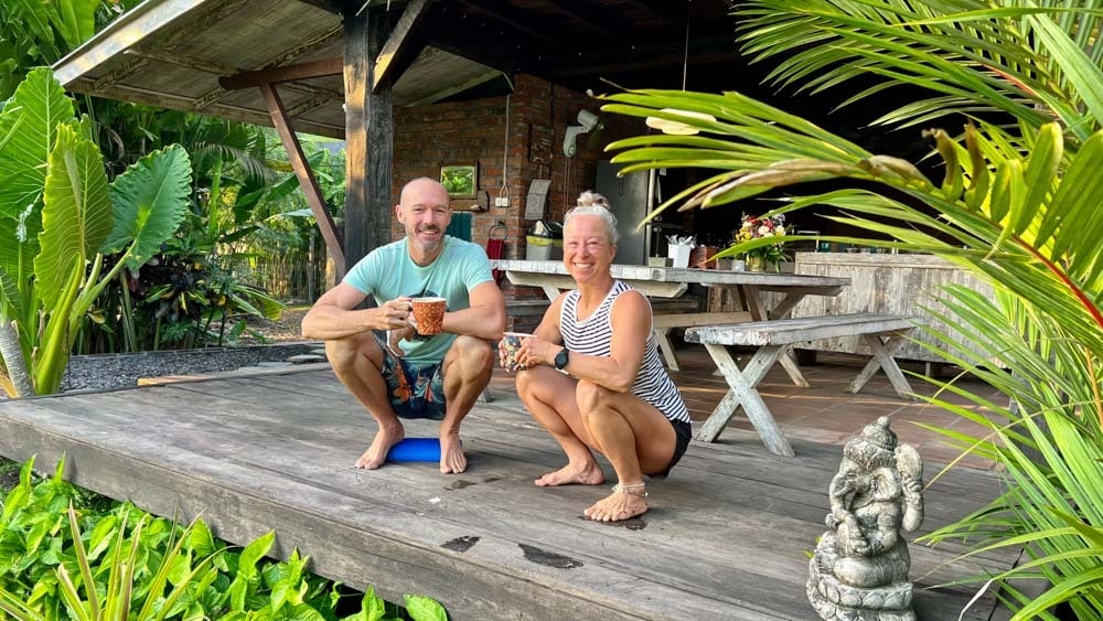 A joyful couple squatting together, wearing happy expressions.