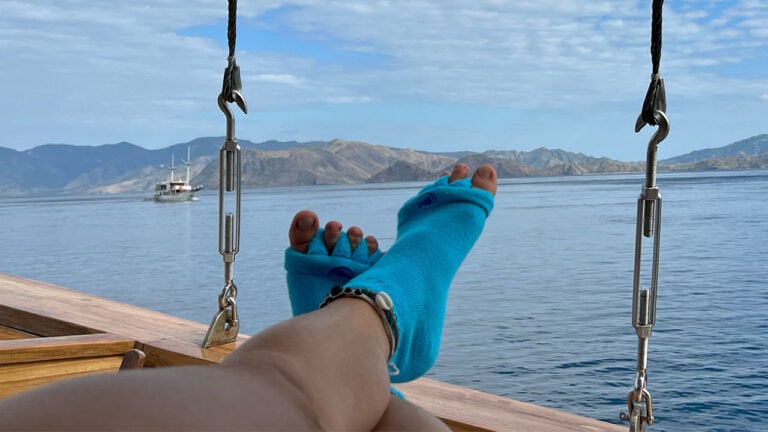 Person wearing toe spacers on a boat with a view on the sea and land.