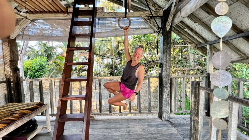 A woman engaging in a playful and beneficial hanging position.