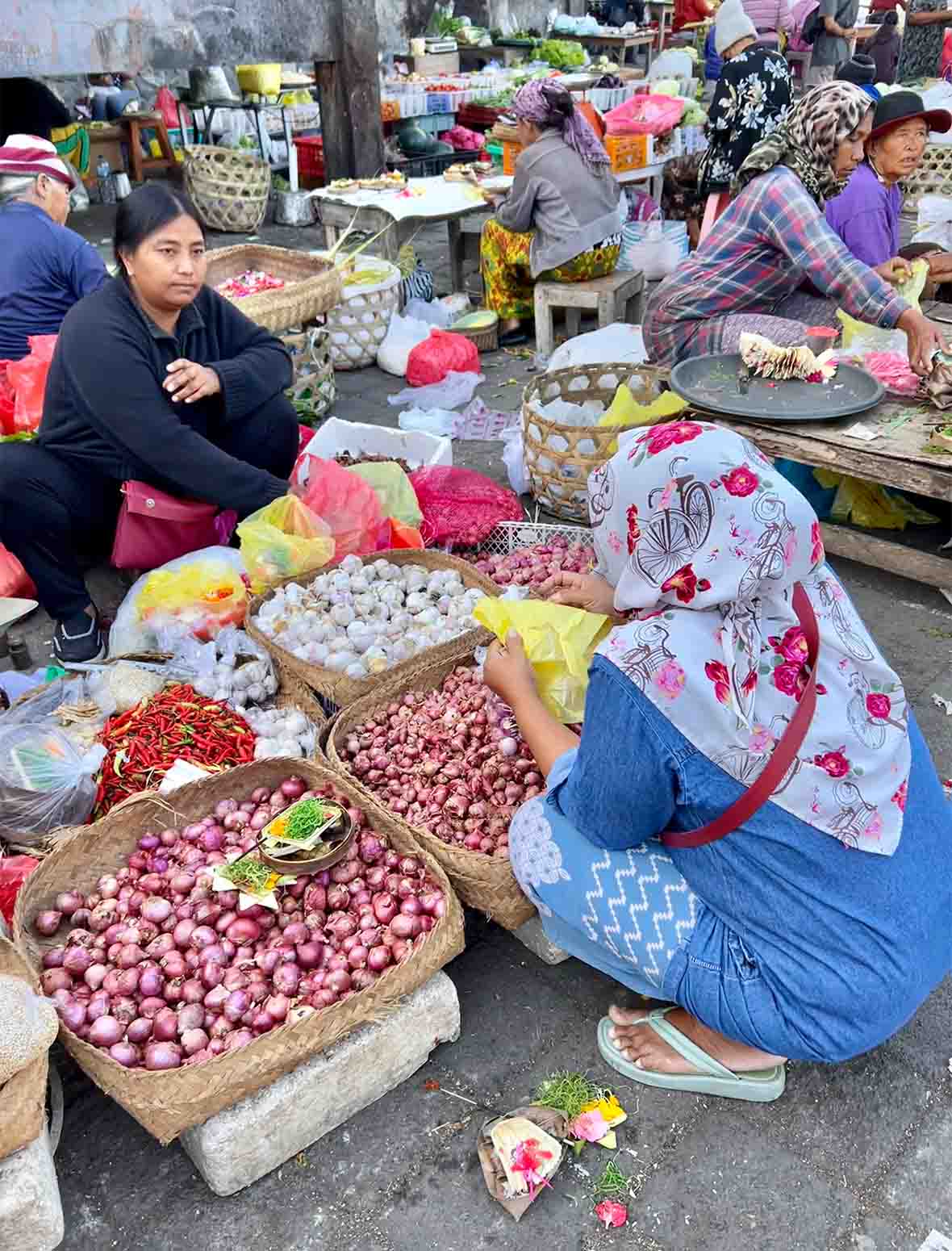 Two women in a local market in Indonesia are floor sitting.